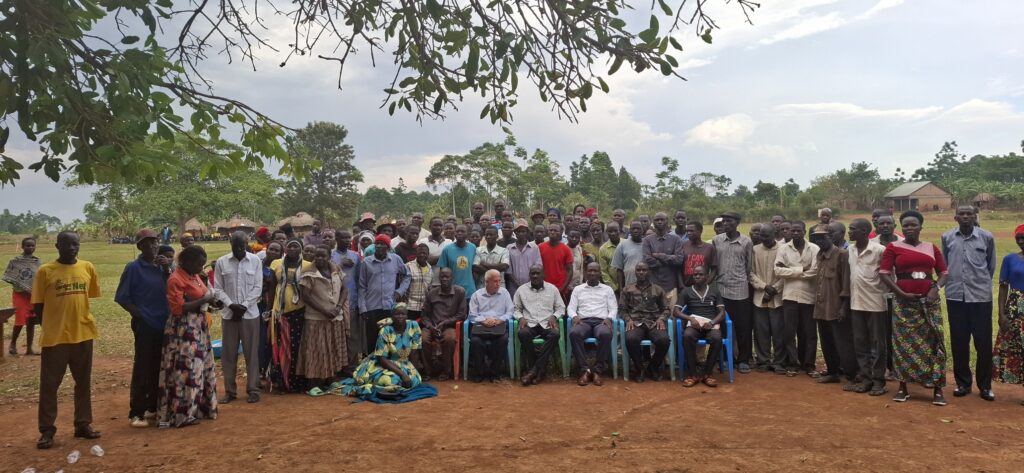 The Director General of the Busoga Consortium, Mr. Mula Anthony, and Namayingo District Chairperson, Mr. Sanya Ronald, in a group photo with the residents of Namayobe Village, Namayingo District.