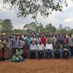 The Director General of the Busoga Consortium, Mr. Mula Anthony, and Namayingo District Chairperson, Mr. Sanya Ronald, in a group photo with the residents of Namayobe Village, Namayingo District.