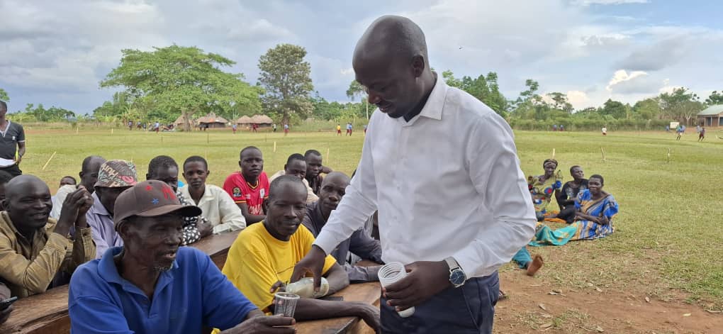 The Director General of the Busoga Consortium, Mr. Mula Anthony, introduces residents of Namayobe Village, Namayingo District, to imported soya milk from Thailand, showcasing its potential as a locally producible product through soybean farming and value addition.