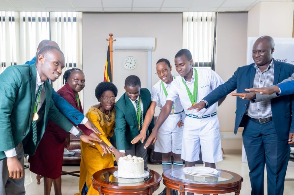 Rt. Hon. Rebecca Kadaga (center) cuts cake with a delegation of students from the Eurasian Schools Debating Championship (ESDC) 2026, celebrating their outstanding achievement on the global stage.PHOTO/Bishop