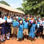 H.E . Ezana Getahun Kassa (c) FAO Country Representative in Uganda, with, Dr. Mula Anthony, (DG/BCD) Hon. Stephen Kisa, HM Mr. Makubo Stephen and District Leadership with pupils of Buteme Light SDA Primary School, group photo during the His official monitoring visit to Busana Model Village in Kamuli District.